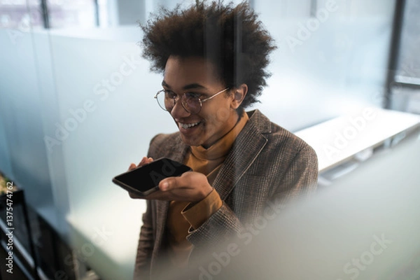 Obraz Businessman using smartphone recording voice message smiling connecting with clients in office