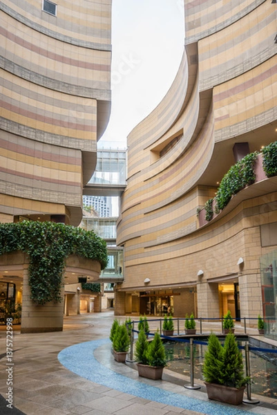 Fototapeta A modern Japanese buildings interior courtyard features curved walls, plants, and a small reflecting pool in Namba, Osaka, Japan