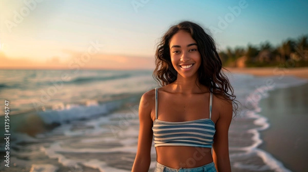 Fototapeta A young teenage girl enjoys the beach at sunset, with the sea and waves in the background. She is wearing summer clothes and the warm sunlight illuminates the scene, creating a relaxed. 