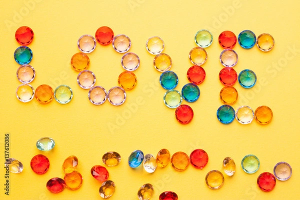 Fototapeta an inscription from multi-colored stones on a yellow background