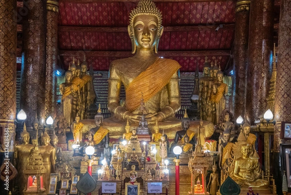 Obraz A Serene Buddha Statue is Surrounded by Beautiful Offerings in an Ornate Temple Structure, Luang Prabang, Laos