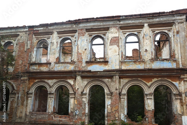 Fototapeta Roofless falling apart abandoned ruined building  with empty windows and plaster going off the walls