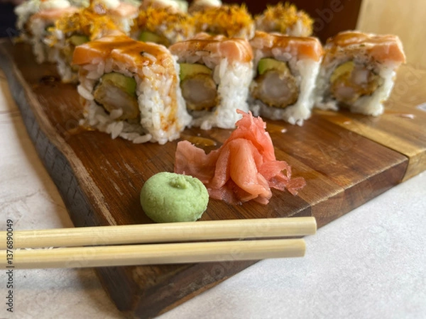 Obraz chopsticks, ginger and wasabi sauce in the foreground with a table of California-style sushi rolls out of focus in the background, Japanese food