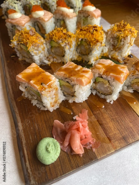 Obraz wooden board with a portion of California style sushi roll with a little ginger and wasabi sauce, vertical