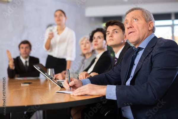 Fototapeta Group of businessmen attentively watching a presentation in a meeting room