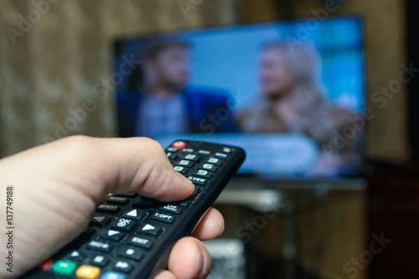 Fototapeta Watching TV and using remote controller