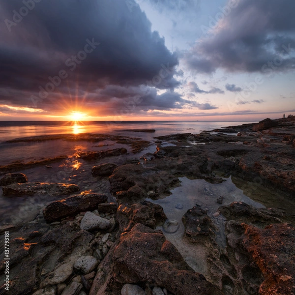 Fototapeta One vivid autumn sunset over curved crevices in the limestone on the shore of Khersones cape, Crimea