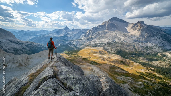 Fototapeta Hiker standing on a mountain peak overlooking a vast mountain range.
The image features a live object (person) within a natural landscape.