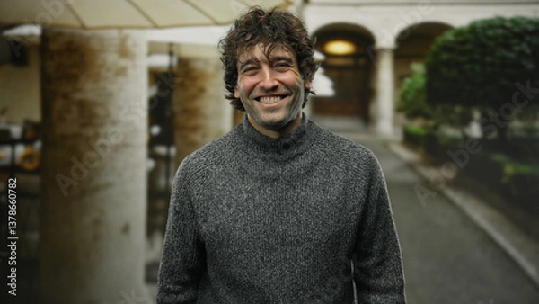 Fototapeta Young man smiling outdoors on a city street, showcasing an attractive and happy expression with a blurred urban background and natural light.