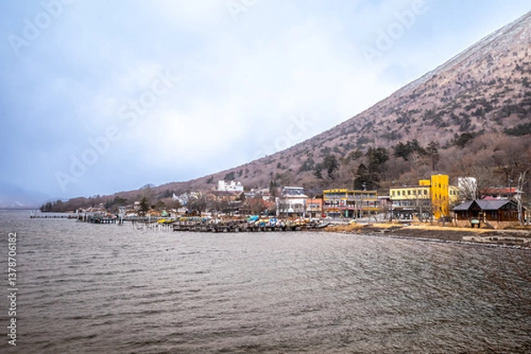 Obraz Lake Chuzenji, on the mountains in Nikko, Japan, during winter season with snow fall under cloudy sky and very cold weather. Japanese letters were name of public gate in Japanese faith.