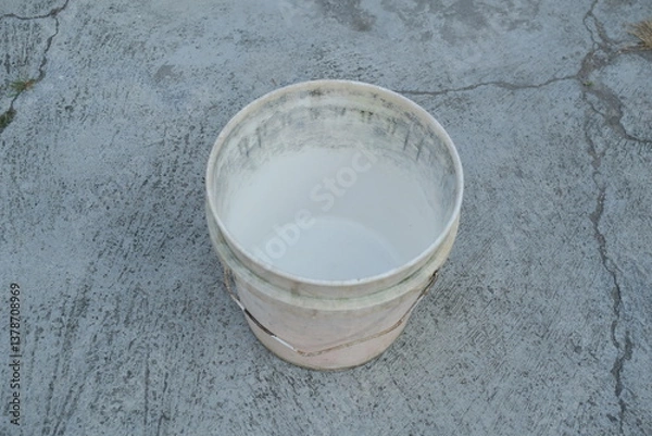 Fototapeta Photo of an empty white bucket on the ground