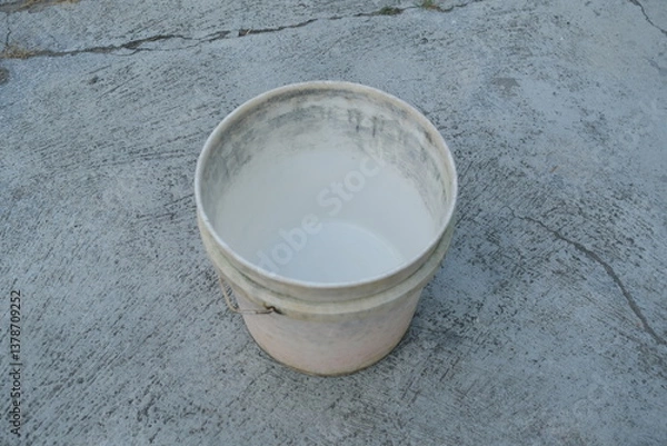 Fototapeta Photo of an empty white bucket on the ground