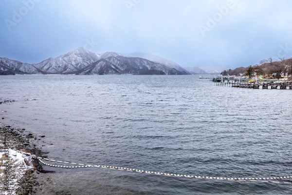 Obraz Lake Chuzenji, on the mountains in Nikko, Japan, during winter season with snow fall under cloudy sky and very cold weather. Japanese letters were name of public gate in Japanese faith.