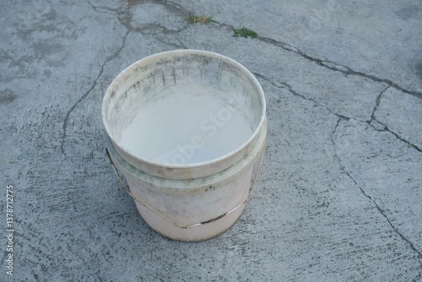 Fototapeta Photo of an empty white bucket on the ground