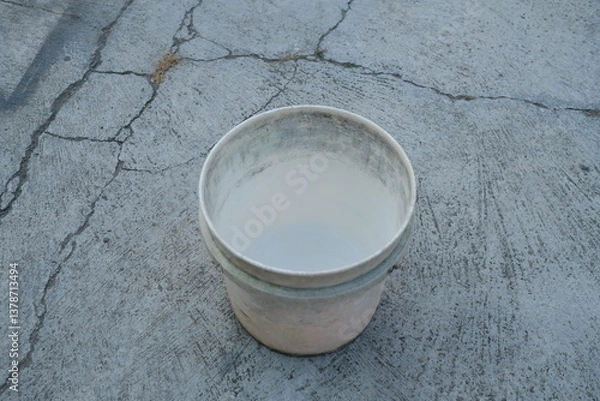 Fototapeta Photo of an empty white bucket on the ground
