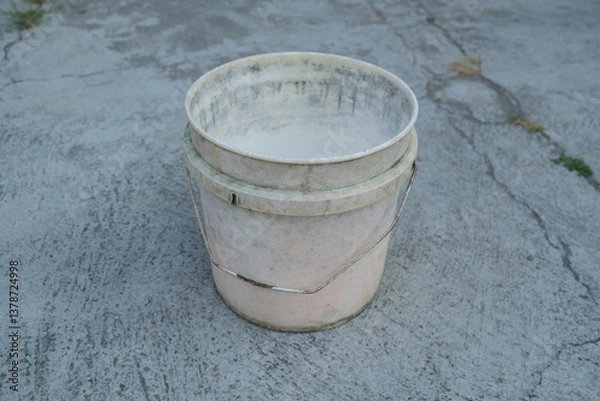 Fototapeta Photo of an empty white bucket on the ground