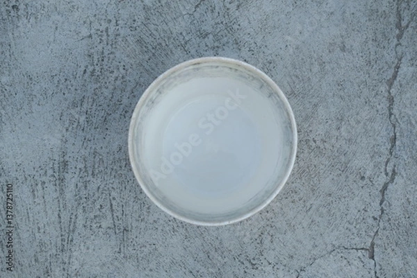 Fototapeta Photo of an empty white bucket on the ground