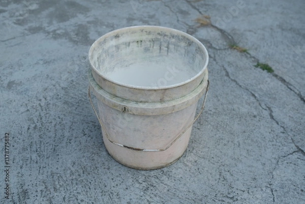 Fototapeta Photo of an empty white bucket on the ground