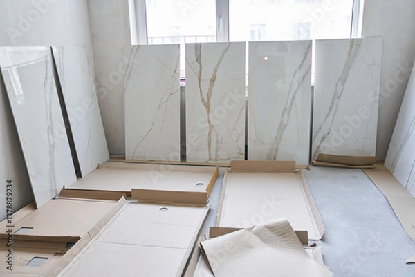 Fototapeta A large marble tile for walls measuring 120 by 60 is displayed in a row, the selection of a pattern on the tile for laying on the walls. On the background of a window under daylight.High quality photo