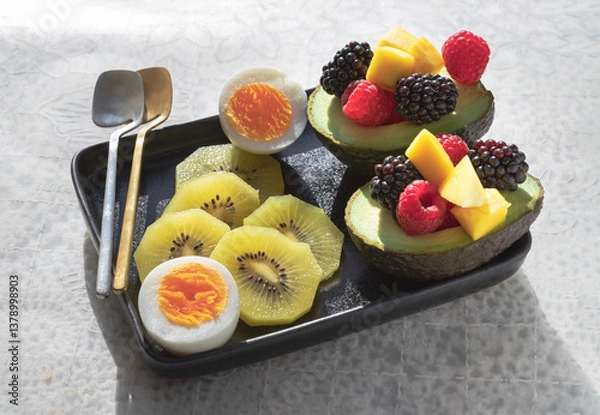 Obraz A colorful healthy food with redberry, blackberry and mango on avocado with golden kiwi and boiled egg on vibrant eating ceramic dish. Breakfast plate with fruits, use it as your wallpaper, poster.
