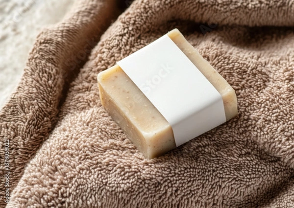 Fototapeta Beige herbal soap bar with blank label on light brown bath towel top view, hygiene product mockup 
