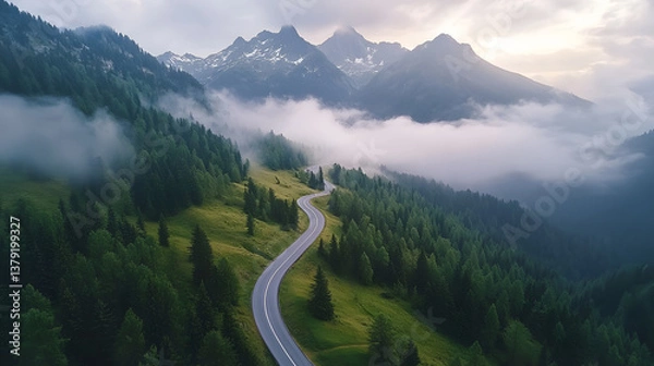 Fototapeta Aerial View of Winding Mountain Road Through the Alps with Snow-Capped Peaks and Morning Fog