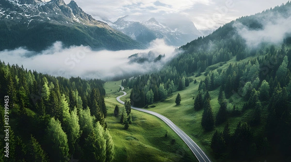 Fototapeta Aerial View of Winding Mountain Road Through the Alps with Snow-Capped Peaks and Morning Fog
