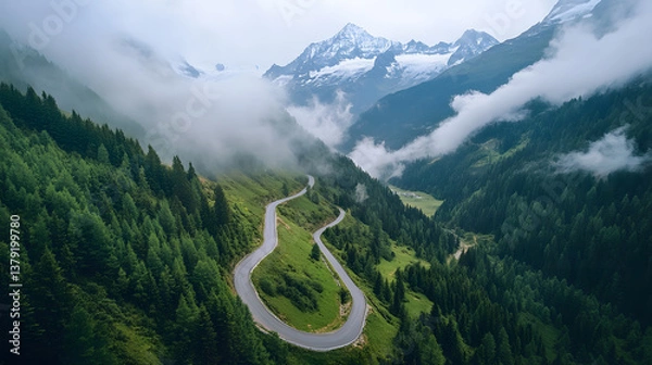 Fototapeta Aerial View of Winding Mountain Road Through the Alps with Snow-Capped Peaks and Morning Fog