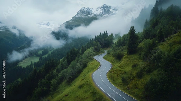 Fototapeta Aerial View of Winding Mountain Road Through the Alps with Snow-Capped Peaks and Morning Fog