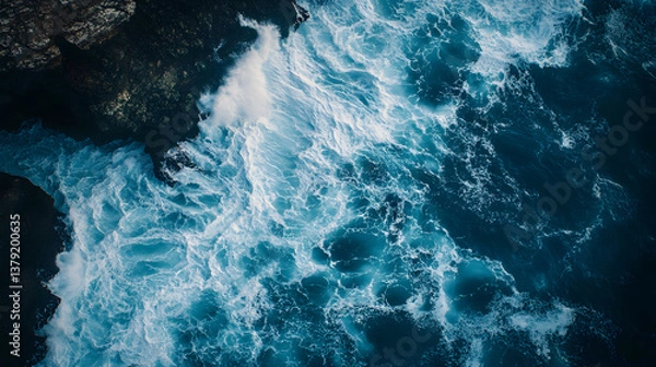 Fototapeta Aerial Top-Down View of Ocean Waves Crashing Against Rugged Cliffs with Dramatic Contrast