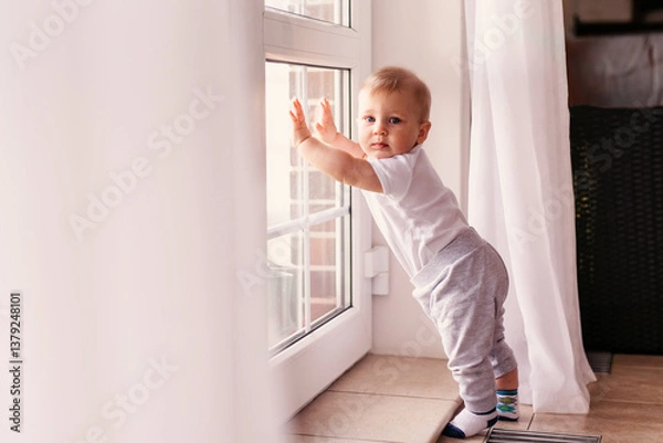 Fototapeta Curious Baby Standing by the Window at Home