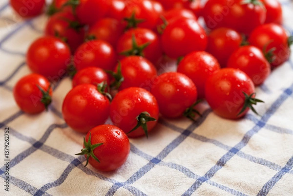 Fototapeta Red ripe cherry tomatoes on checked white towel, focus on foreground