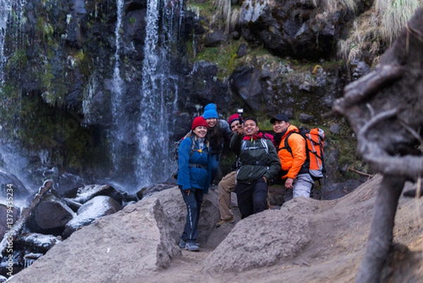 Fototapeta Group of hikers taking a selfie in front of a waterfall in the mountains