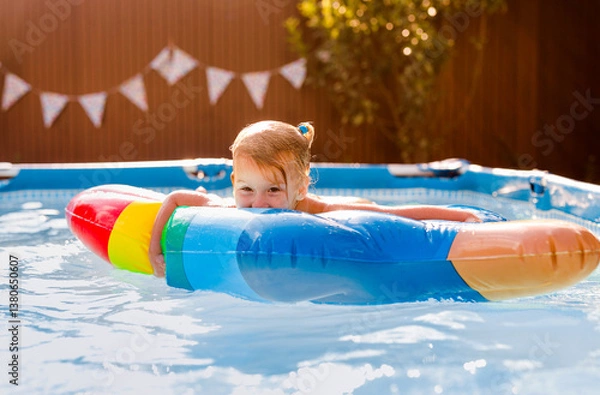 Fototapeta Smiling kid having fun in pool on colorful inflatable toy at summer day