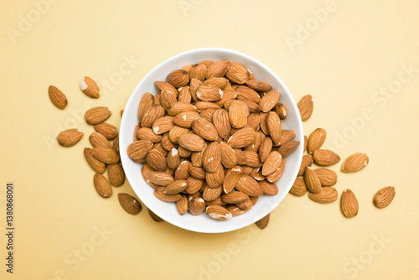Obraz Top view of almonds into bowl on yellow background.