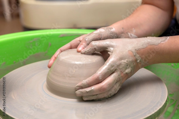 Fototapeta The process of kneading and manufacturing artisanal ceramics and clay by hand and with a wheel, showing the step-by-step process by the hands of a ceramics professional.
