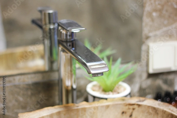 Fototapeta close-up of cleaned bathroom sink faucet in a stylish bathroom with wooden sink and a plant and tissues in the interior