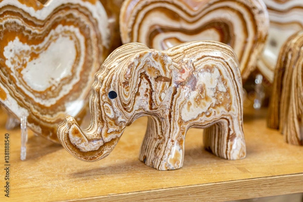 Obraz Elephant made of onyx. Elephant statue made of natural onyx stone stands on display case of souvenir shop. Close-up of elephant figure made of onyx. Detailed Close-up reveals mineral patterns of onyx.