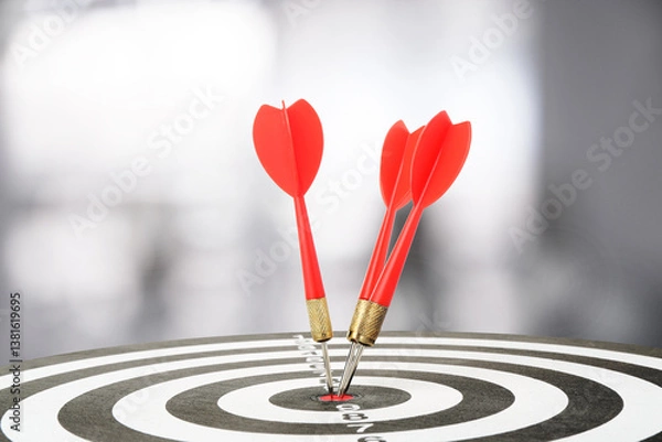 Fototapeta Targeting and business success. Darts sticking in center of dartboard in office, closeup