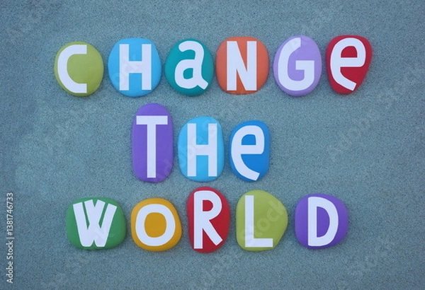 Fototapeta Change the world, creative social slogan composed with multi colored hand painted stone letters over green sand
