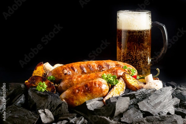 Fototapeta Kiełbaski grillowane na węglu drzewnym z piwem w tle