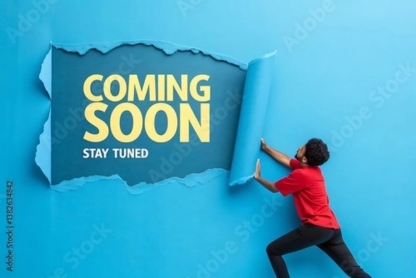 Fototapeta A young man reveals a Coming Soon message creating anticipation and excitement with a vibrant blue background and bold text stay tuned for what s next