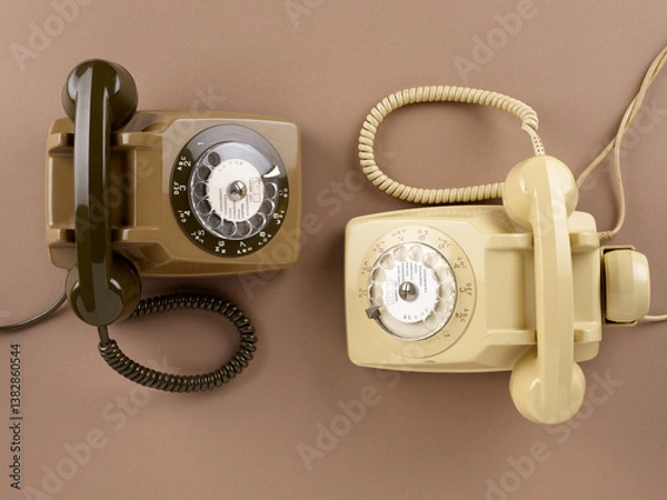 Obraz Vue aérienne de deux téléphones à cadran de couleur marron et beige avec câble et combiné, sur un fond ton sur ton.