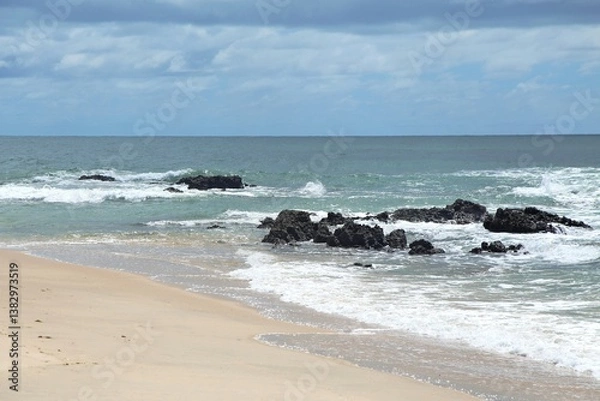 Obraz Blue sea water in Coqueiros beach, close to Joao Pessoa city, Paraiba, Brazil. Open wide ocean with waves crashing on reefs rocks at water edge, beach sand.