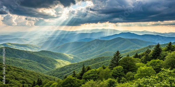 Fototapeta Panoramic mountain landscape, dramatic sunbeams through clouds, rolling green hills, misty valleys, blue ridges, forest silhouettes, crepuscular rays, ethereal light, atmospheric perspective, scenic 