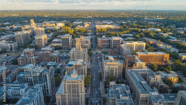Fototapeta Aerial shot of a city with buildings, trees, and a long straight street in the daytime