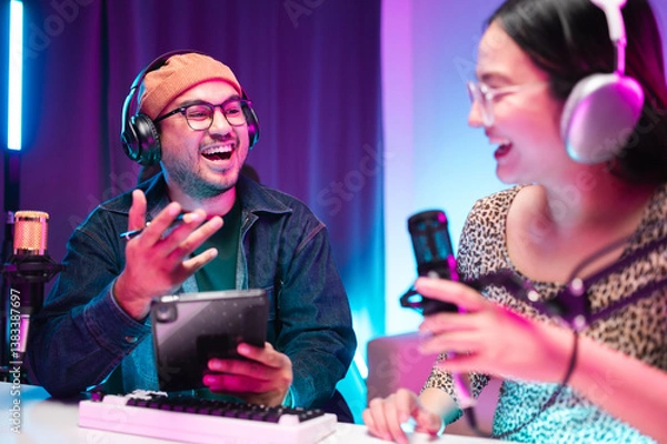 Fototapeta Teenagers, men and women, host podcasts in a room using LED lights, computers, headphones, condenser microphones, and tablets to share their knowledge and experiences through live online broadcasts.