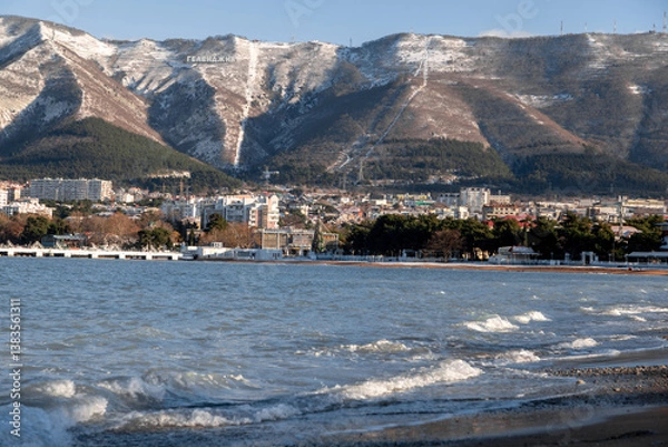 Obraz A beautiful mountain range with a city in the background. The city is full of buildings and the water is calm