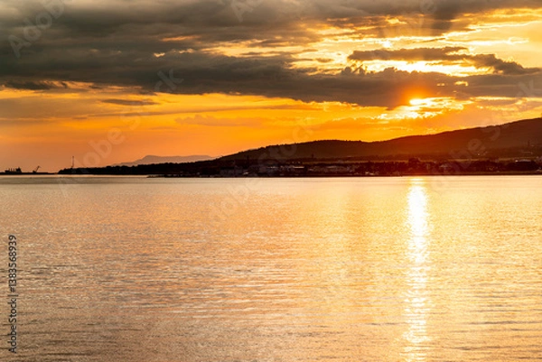 Obraz The sun is setting over the water, creating a beautiful orange and pink sky. The water is calm and still, reflecting the colors of the sky. The scene is peaceful and serene