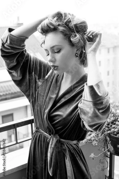 Obraz Bellissima ragazza in vestaglia fuma una sigaretta sul terrazzo  